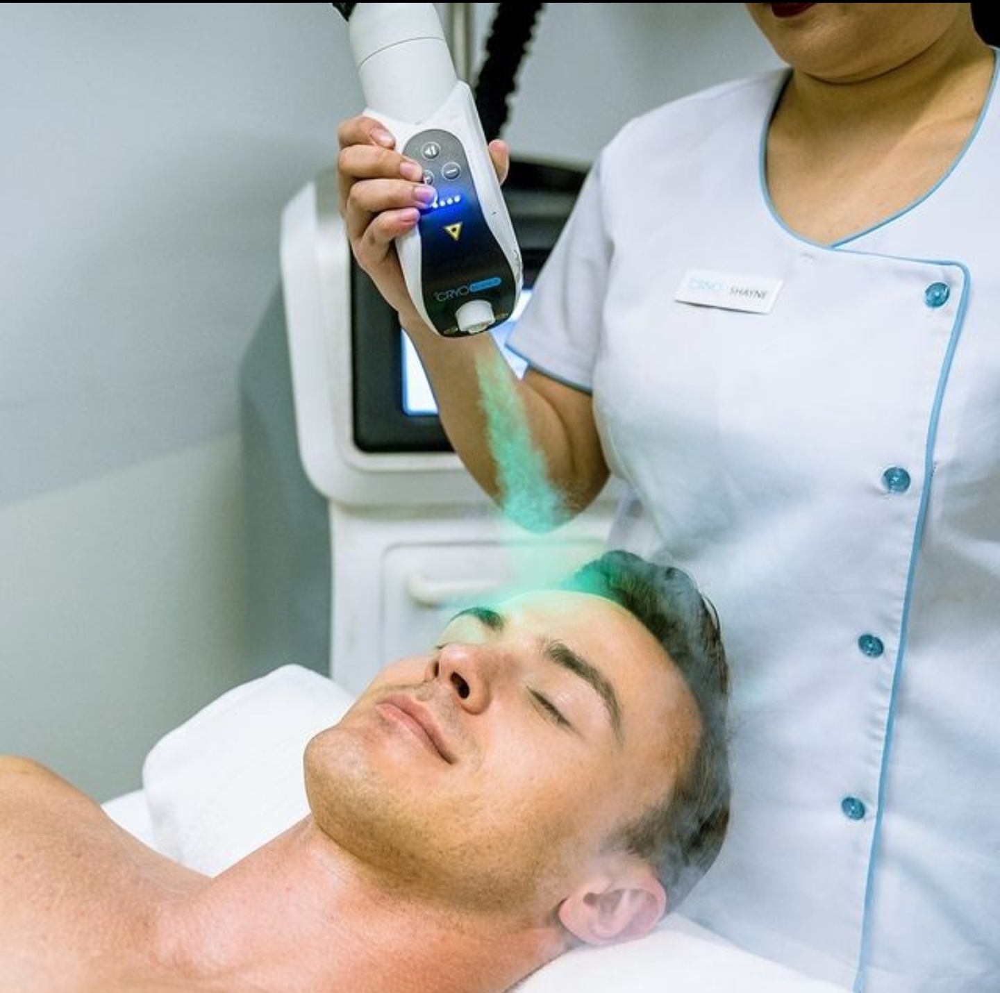 Client receiving a cryo facial as a fine cold mist is directed across the forehead